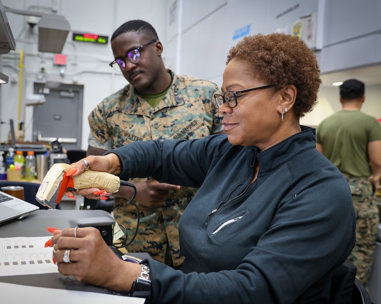 GySgt Rasheem S. Waxter, inventory management chief, observes as Linda B. Woods, a supply technician, conducts a sub-inventory transfer using Global Combat Service Support (Marine Corps GCSS-MC). Woods scans the serial numbers of each asset listed on the Department of Defense Form-1348 (DD Form 1348). The ability to scan enhances accuracy and ensures timely transfers of assets to virtual locations. The 2nd Force Storage Battalion receives DD Forms 1348 containing up to 500 assets on a single document.