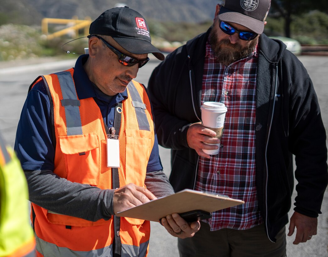 Jon Rishi, senior biologist with the U.S. Army Corps of Engineers Los Angeles District’s Operations Division, left, takes notes during a walkthrough of Lario Park Staging Area March 19 in Azusa, California. At right is Trevor Snyder, LA County Drainage Area program manager with the USACE LA District’s Operations Division.