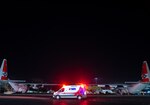 Emergency medical services personnel wait in an ambulance behind two Coast Guard Air Station Barbers Point HC-130 Hercules airplanes on the ramp at the air station in Kapolei, Hawaii, March 20, 2025. An Air Station Barbers Point HC-130 Hercules airplane crew conducted a medical transport for an ailing man on Kwajalein Atoll. (U.S. Coast Guard photo by Petty Officer 2nd Class Tyler Robertson)