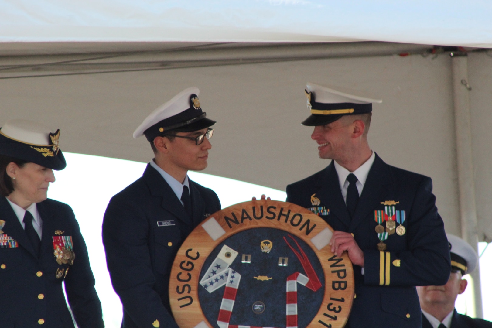 Rear Adm. Megan Dean, commander of Coast Guard District 17, and Coast Guard Cutter Naushon (WPB 1311) crewmembers presenting an award during the Naushon decommissioning ceremony in Homer, Alaska, March 21, 2025. Naushon has been stationed in Homer since 2016 and has since responded to over 50 search-and-rescue cases and completed nearly 900 law enforcement sorties. - U.S. Coast Guard photo by Seam Sydney Sharpe