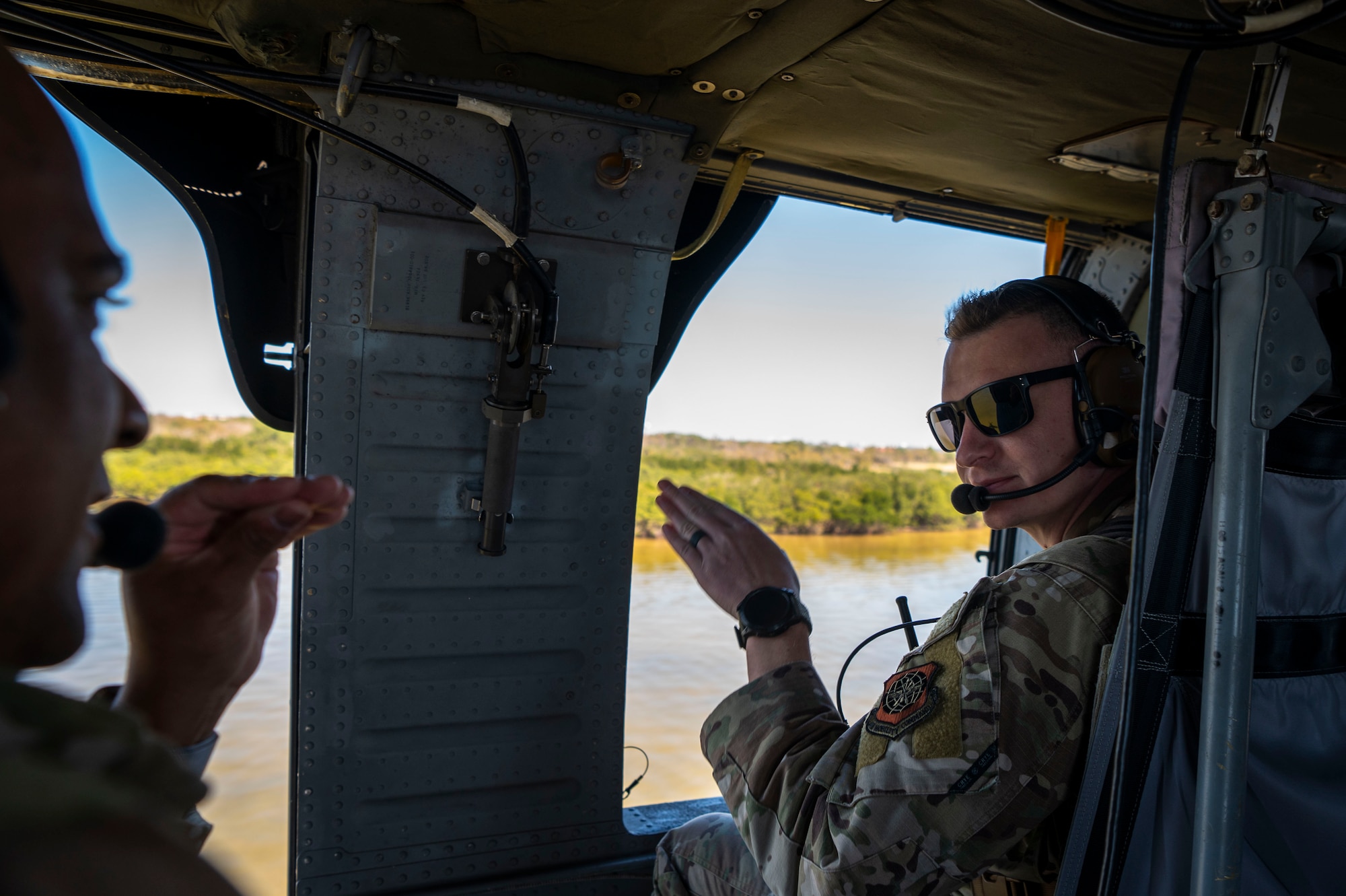 U.S. Air Force Master Sgt. Hector Rivera-Bonilla, 6th Security Forces Squadron Coastal Observation Aerial Security Team superintendent, left, communicates with Tech. Sgt. Joseph Villano, 6th SFS COAST program manager, right, during a flight aboard a UH-60 Black Hawk at MacDill Air Force Base, Florida, March 7, 2025.