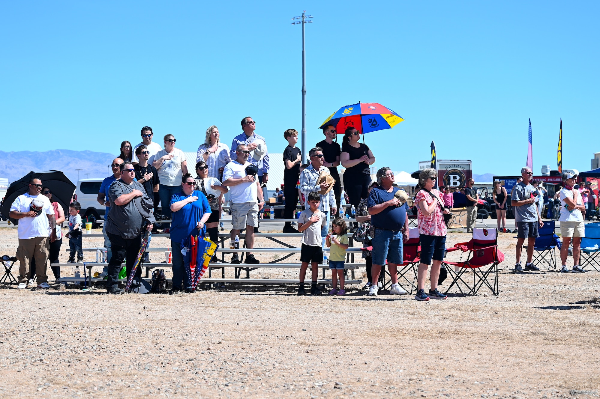 Visitors place their hands over their hearts for the national anthem at Davis-Monthan Air Force Base, Arizona, March 22, 2025. The Thunderbirds were the heading act for the 2025 Thunder and Lightning Over Arizona Air Show March 22 and 23. (U.S. Air Force photo by Senior Airman Andrew Garavito)