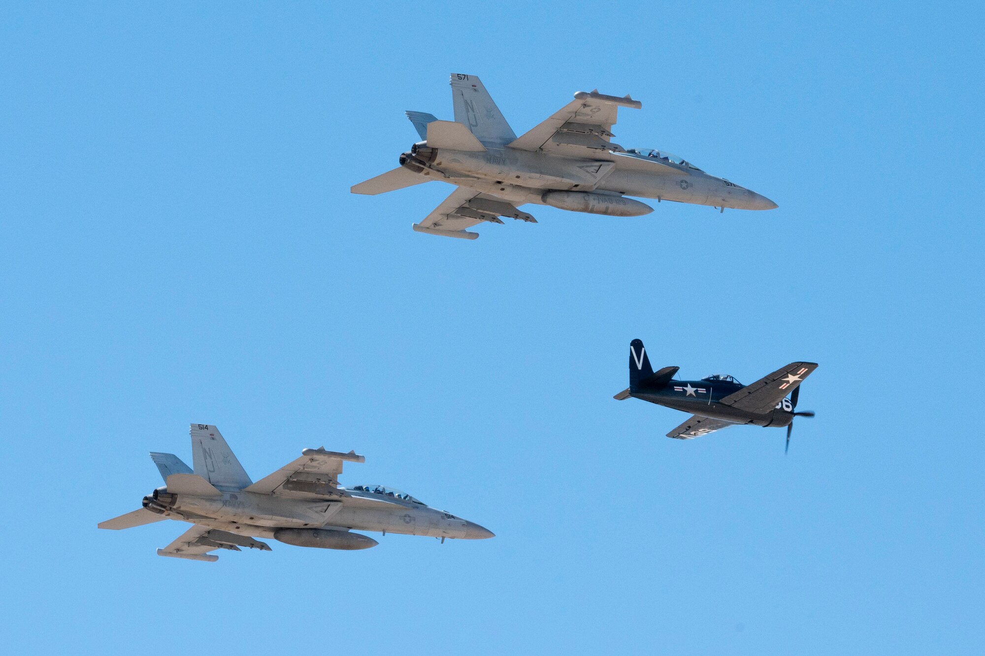 Two U.S. Navy EA-18G Growlers flies with a Grumman F8F Bearcat aircraft over Davis-Monthan Air Force Base, Arizona, March 22, 2025. The Growler is an Airborne Electronic Attack aircraft equipped with an electronic warfare suite capable of carrying out a wide range of enemy defense suppression missions. (U.S. Air Force photo by Airman Samantha Melecio)