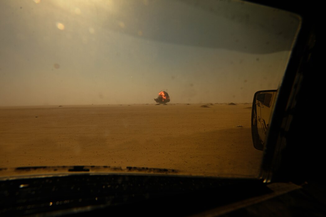 Smoke and fire billow in the distance after a controlled detonation.