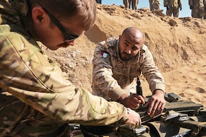 A host nation service member work with a member of the U.S. Air Force.