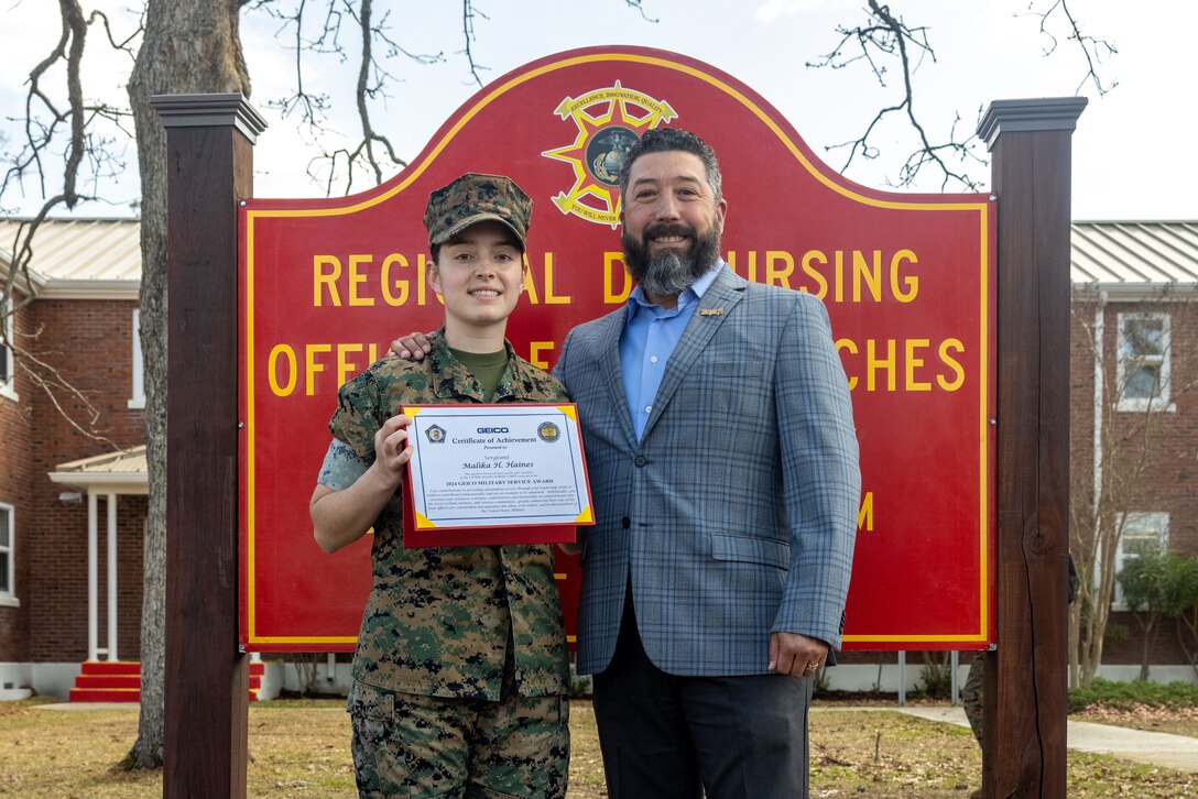 U.S. Marine Corps Sgt. Malika Haines, left, a finance technician with Headquarters and Service Battalion, 2nd Marine Logistics Group, poses for a photo with Retired Sergeant Major Luis Levia, Manager of GEICO Military Affairs Team, following an award ceremony on Marine Corps Base Camp Lejeune, North Carolina, March 17, 2025.  Haines won the 2024 GEICO Service Member of the Year Award in recognition of her influence, both on and off duty within her civilian and military communities, throughout her Marine Corps career. (U.S. Marine Corps photo by Cpl. Christian Salazar)