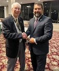 Director Omar Lopez poses for a photo with Roy Mosteller at the 2023 NCIS Association’s National Conference in Nashville.