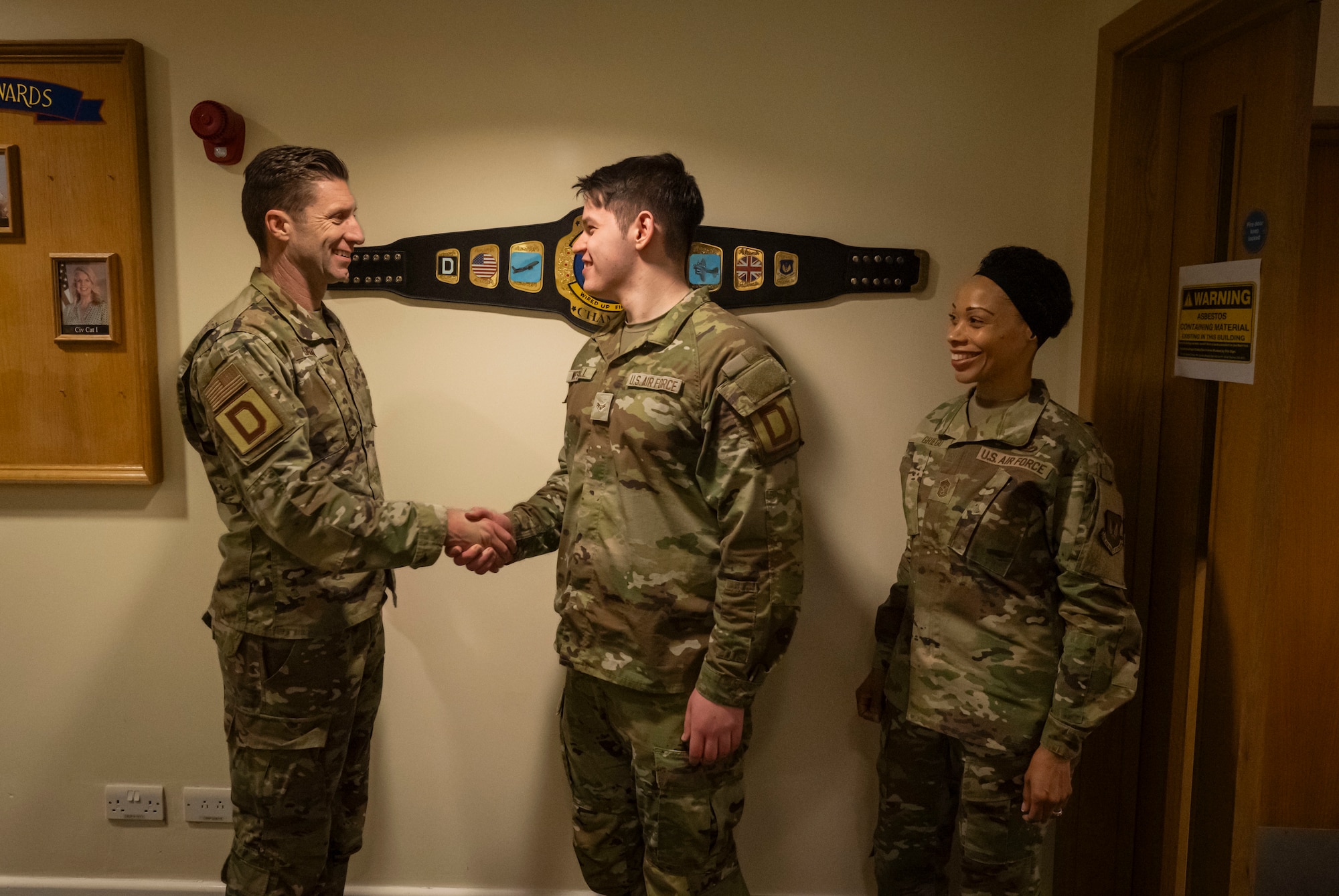U.S. Air Force Airman 1st Class Michael Westfall, center, 100th Communications Squadron cyber system technician, accepts a commander’s coin presented by the 100th Air Refueling Wing command team at RAF Mildenhall, England, March 21, 2025.
