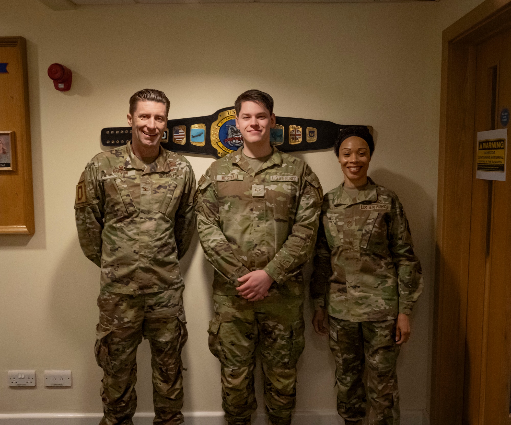 U.S. Air Force Airman 1st Class Michael Westfall, center, poses for a picture with Col. Ryan Garlow, left, 100th Air Refueling Wing commander, and Chief Master Sgt. Tiffany Griego, 100th ARW command chief, at RAF Mildenhall, England, March 21, 2025.