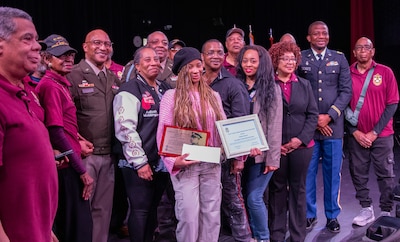 Aaliyah Johnson, center, the 2025 recipient of the Captain Walter H. Dyett award, is joined by her parents, members of the 8th Infantry Association, school officials from the Walter H. Dyett High School for Fine Arts in Chicago, and Maj. Gen. Rodney Boyd, The Adjutant General of Illinois and Commander of the Illinois National Guard, during the third annual Captain Walter H. Dyett award ceremony March 19.