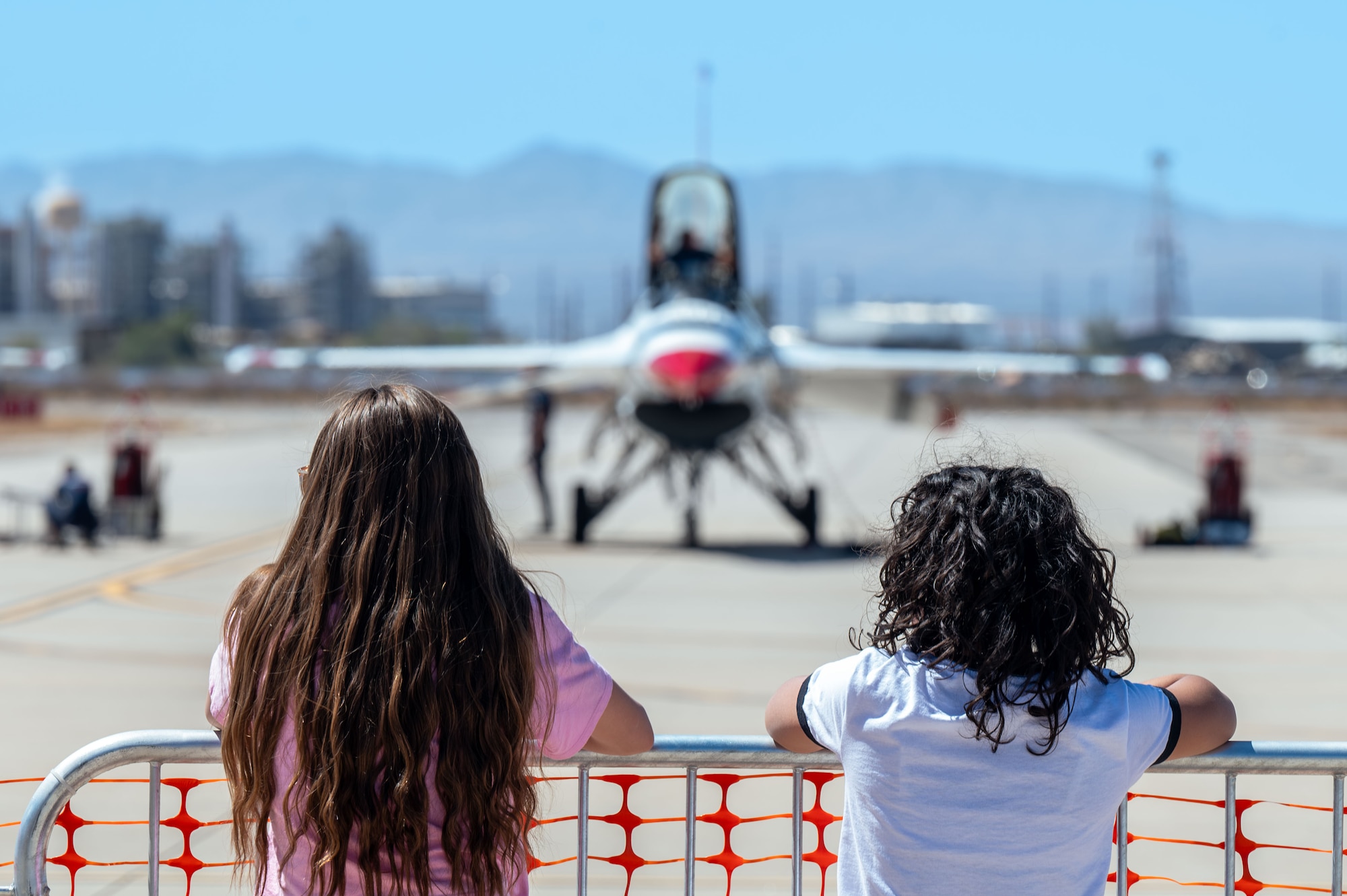 Attendees of the Thunder and Lightning Over Arizona Air Show rehearsal watch the U.S. Air Force Thunderbirds perform maintenance on their aircraft at Davis-Monthan Air Force Base, Arizona, March 21, 2025. The Thunderbirds consist of eight pilots, four support officers, three civilians and over 120 enlisted personnel. (U.S. Air Force photo by Senior Airman Jasmyne Bridgers-Matos)