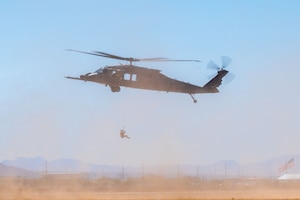 A U.S. Air Force pararescueman descends from an HH-60W Jolly Green II aircraft during the Thunder and Lightning Over Arizona Air Show at Davis-Monthan Air Force Base, Arizona, March 21, 2025. Members of the 563rd Rescue Group performed a combat search and rescue demonstration to showcase their mission. (U.S. Air Force photo by Senior Airman Jasmyne Bridgers-Matos)