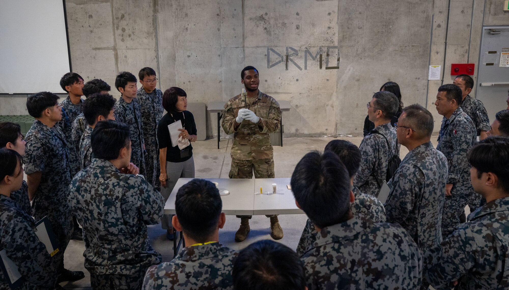 A U.S. Air Force service member demonstrates the proper use of chem gear to a group of Japanese Air Self-Defense Force members.