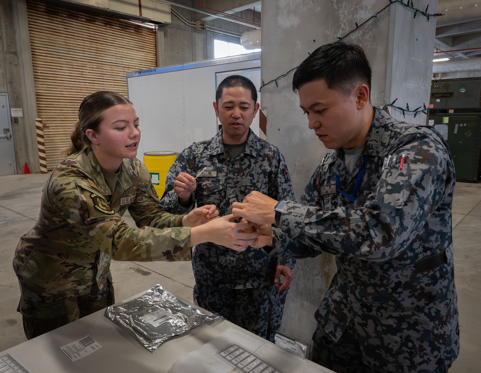 A U.S. Air force service member instructs two Japanese Air Self-Defense Force members.
