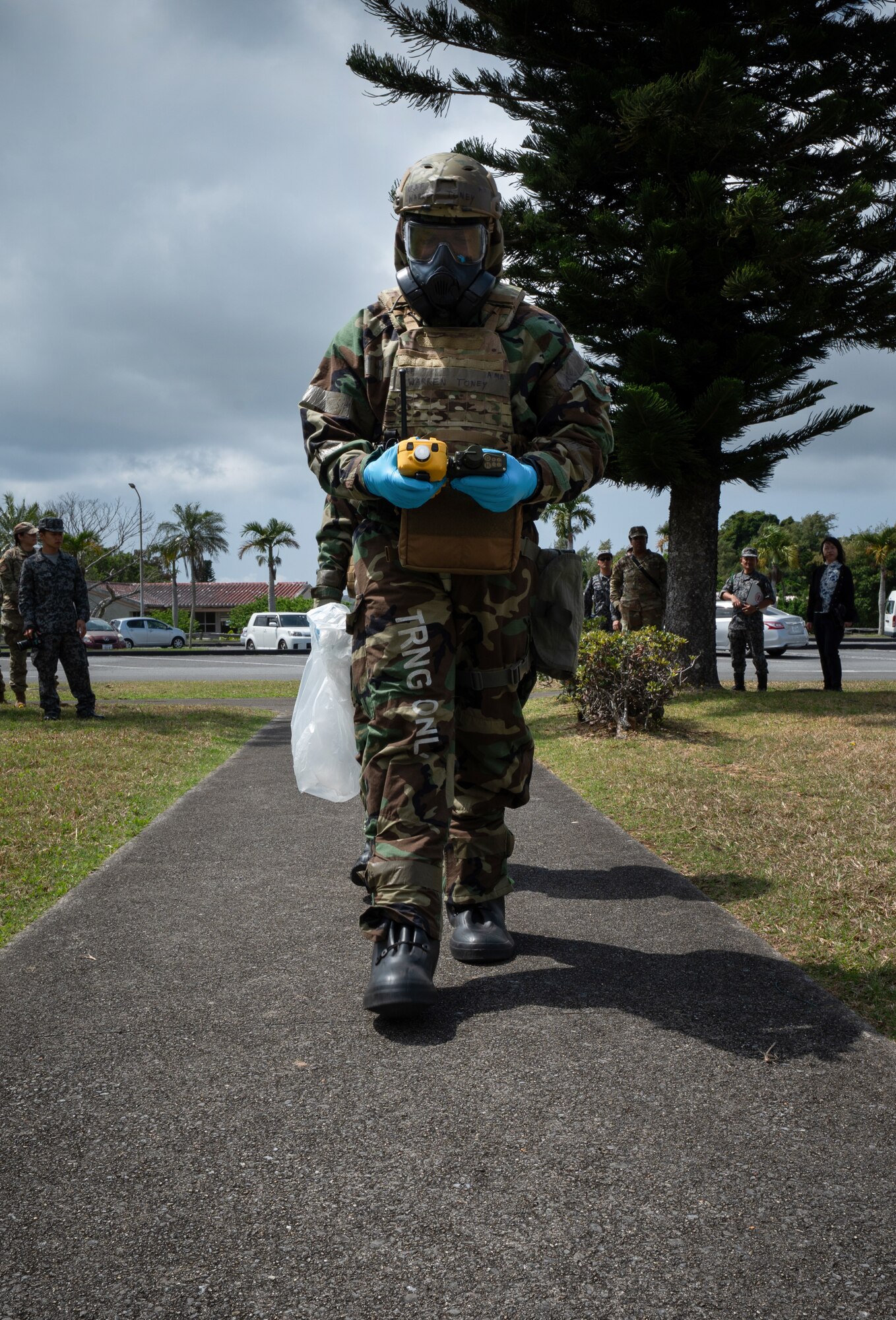 Japanese Air Self-Defense Force members watch U.S. service members in chem gear perform a parr sweep.