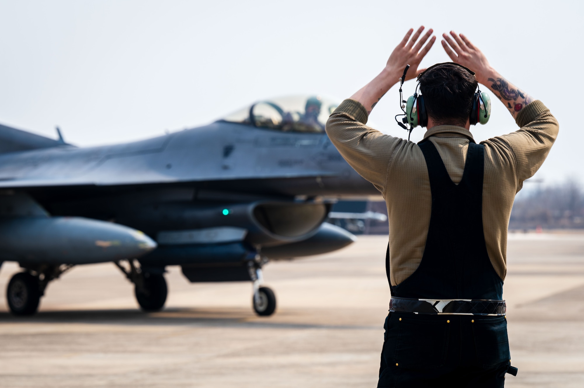 A U.S. Air Force crew chief assigned to the 51st Fighter Wing marshals an F-16 Fighting Falcon aircraft in South Korea, March 7, 2025. The 51st Fighter Wing and 11th Air Task Force worked together to land, refuel and store the aircraft in preparation for Freedom Shield 25. (U.S. Air Force photo by Senior Airman Jasmyne Bridgers-Matos)