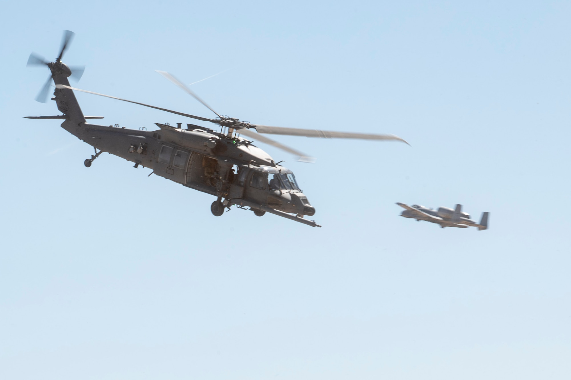 A U.S. Air Force HH-60W Jolly Green II helicopter flies past an A10C Thunderbolt II aircraft during the 2025 Thunder and Lightning Over Arizona Air Show at Davis-Monthan Air Force Base, Arizona, March 22, 2025. The aircraft participated in a combat search and rescue demonstration during the air show.