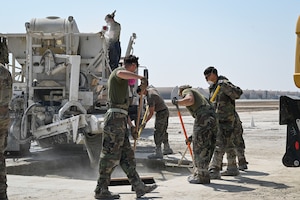 U.S. Marine Corps combat engineers with Marine Wing Support Squadron 172, Marine Aircraft Group 36, 1st Marine Aircraft Wing, smooth out layers of concrete in a Rapid Airfield Damage Recovery after a simulated attack during Freedom Shield 25 at Kunsan Air Base, Republic of Korea.