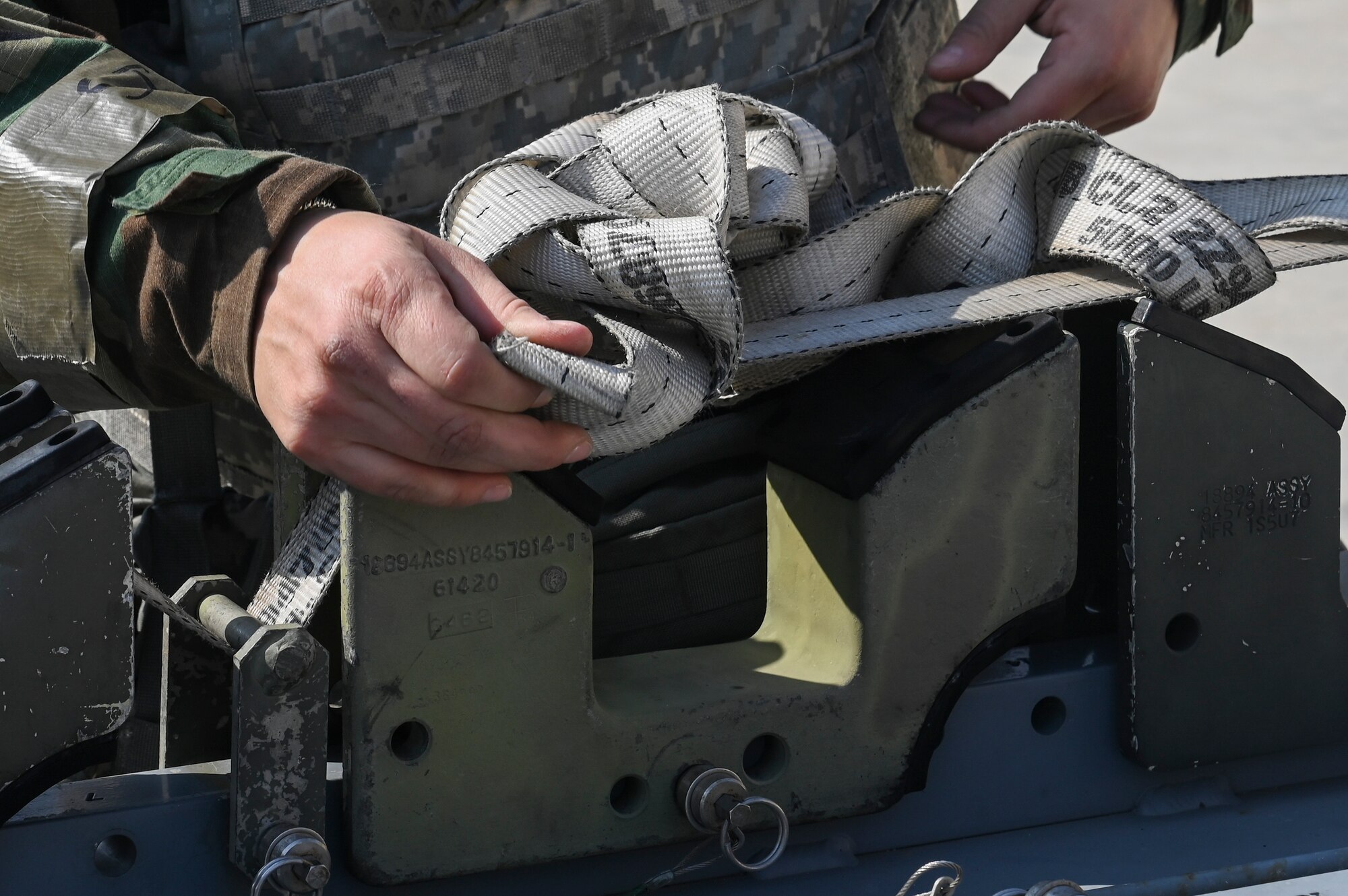 U.S. Air Force Staff Sgt. Candice Croes, 8th Maintenance Squadron conventional maintenance support craftsman, ties a munition strap to secure a training munition during Freedom Shield 25 at Kunsan Air Base, Republic of Korea.