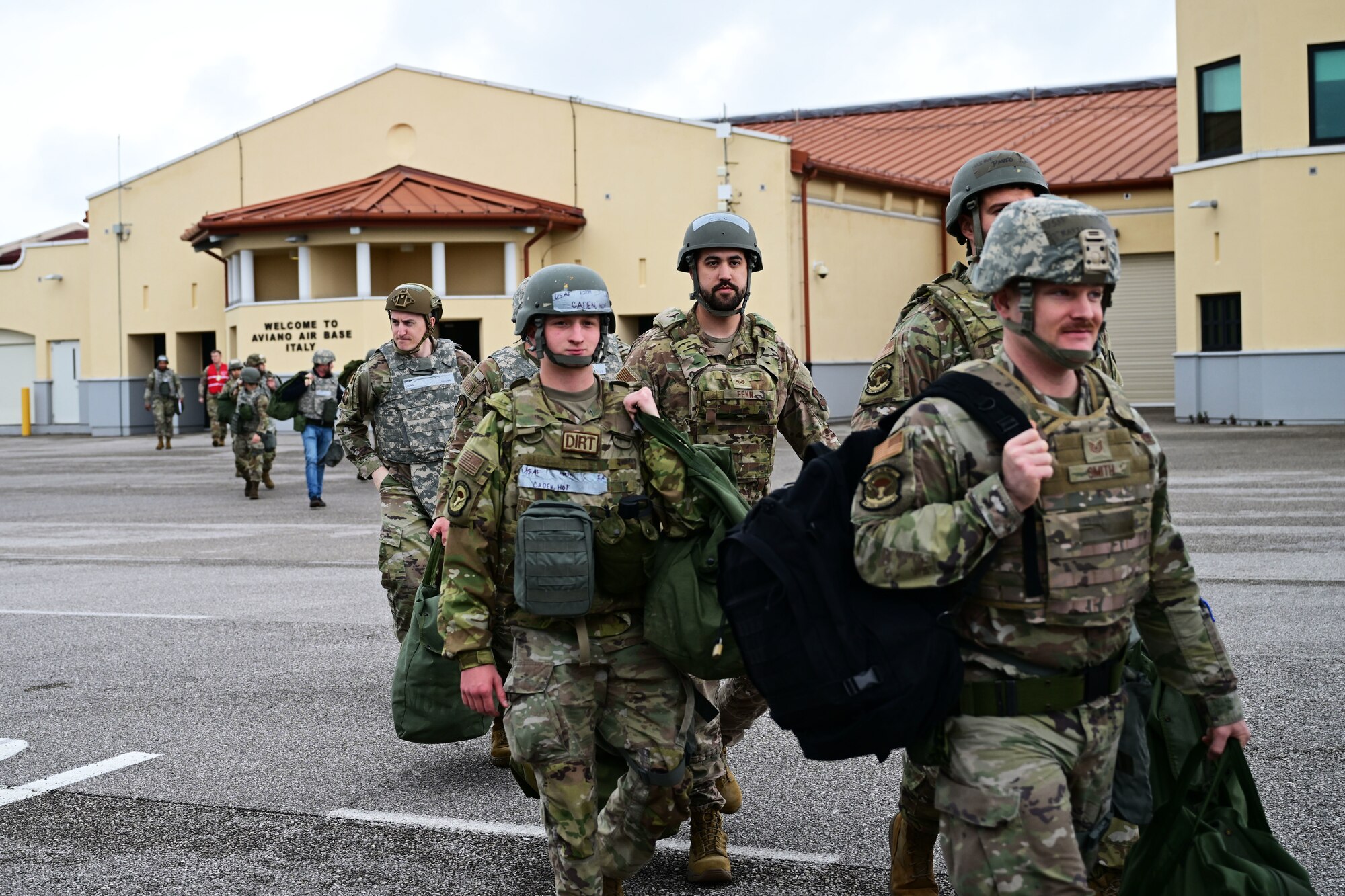 U.S. Air Force Airmen walk away from a building towards the bus in preparation for mock deployment.