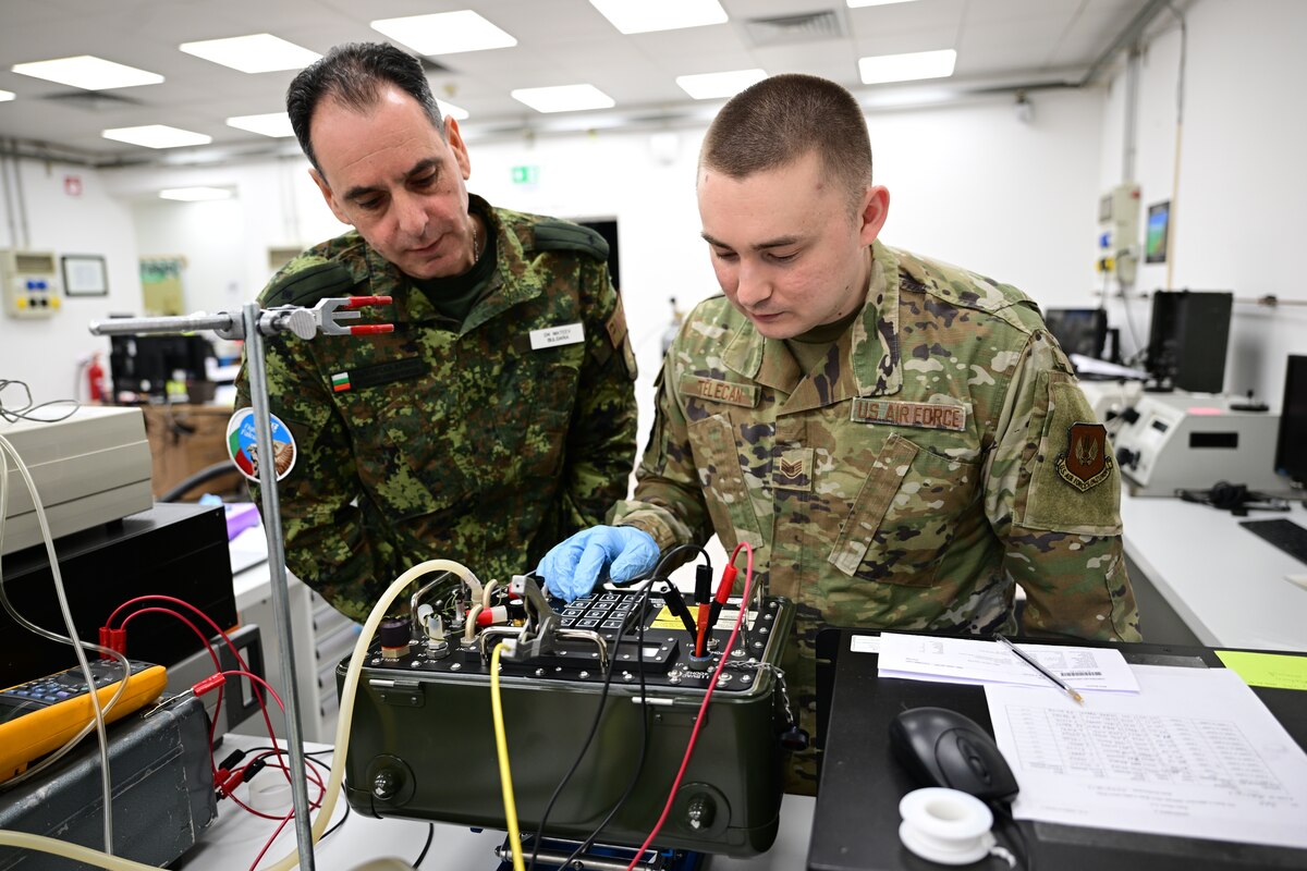 U.S. Airmen and Bulgarian service member analyze equipment.
