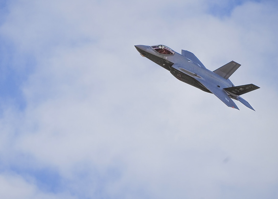 F-35 Lightning flies through a sky with some clouds