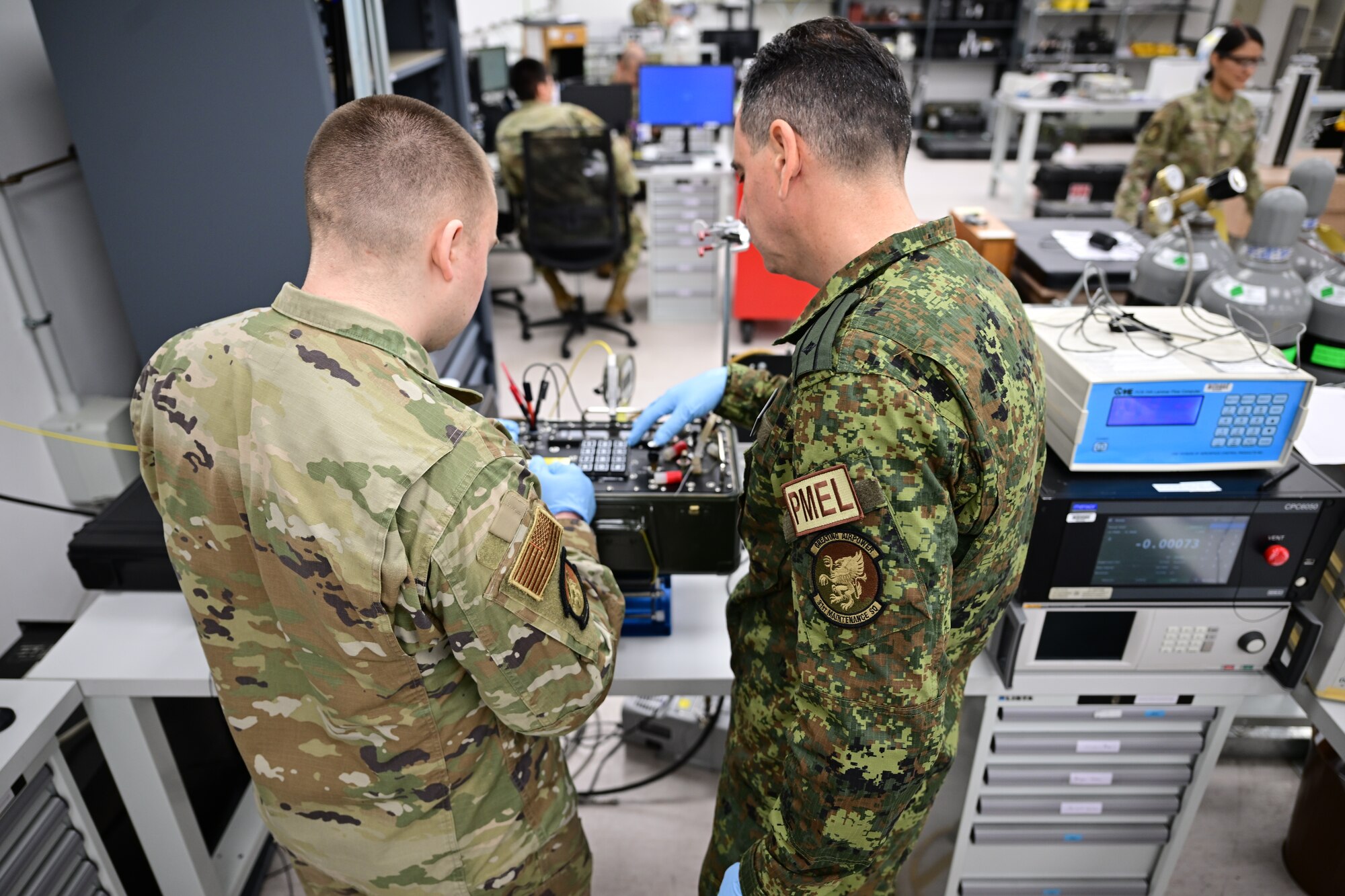 U.S. Airmen and Bulgarian service member work with pressurizing equipment.