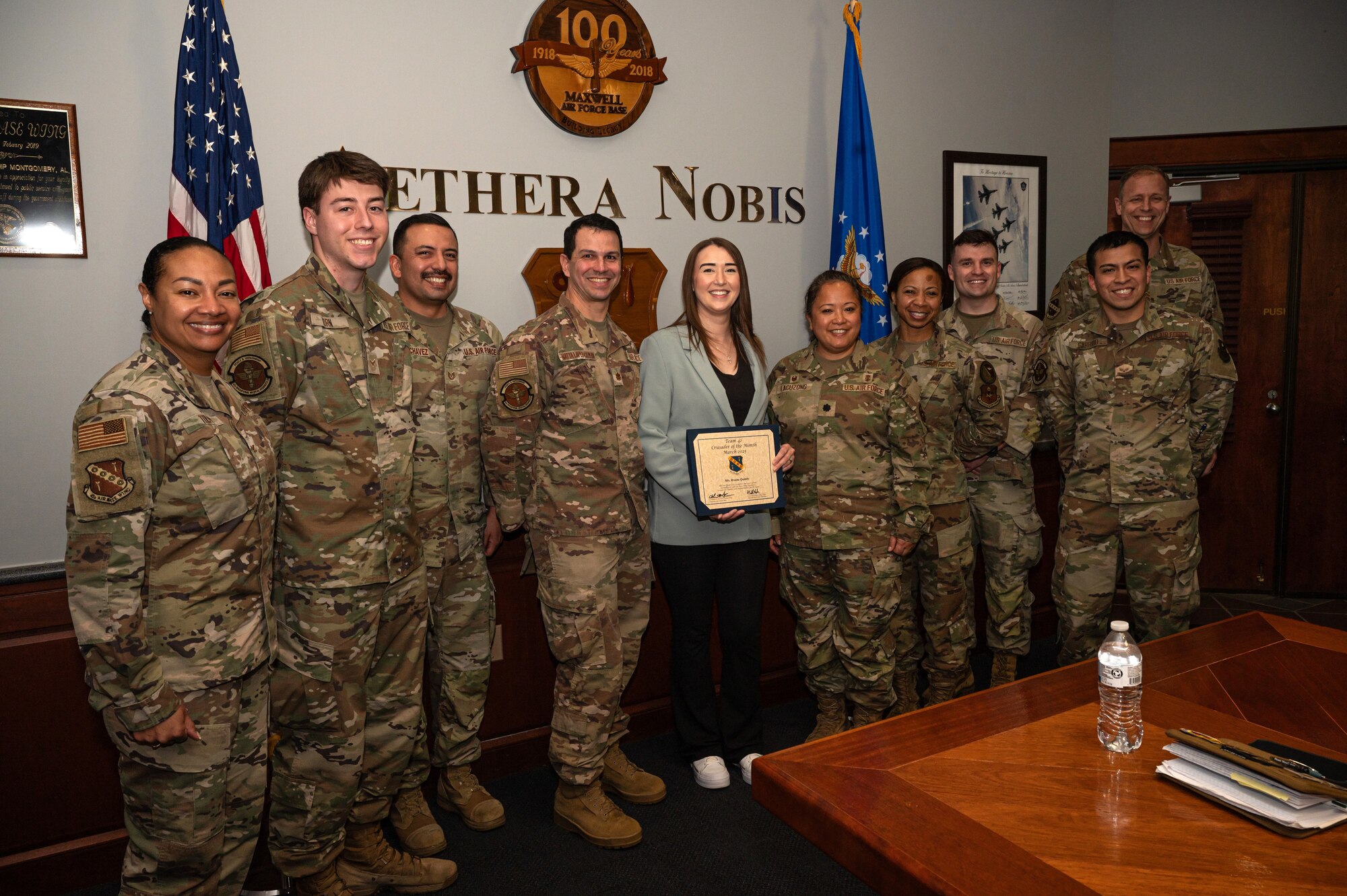 Breana Quimby, middle, 42nd Operational Medical Readiness Squadron environmental health technician, poses for a photo with the 42nd OMRS team after receiving the Crusader of the Month award for March from U.S. Air Force Col. Shamekia Toliver, far left, 42nd Air Base Wing commander, and Chief Master Sgt. Caleb Vaden, far right, 42nd ABW command chief, at Maxwell Air Force Base, Alabama, March 20, 2025.