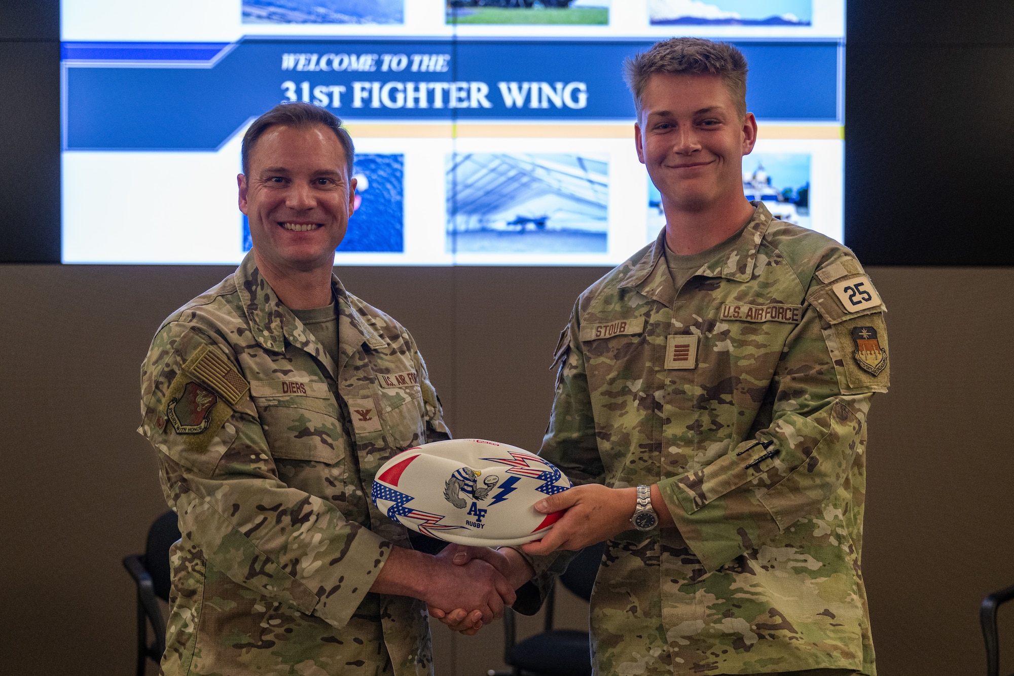 United States Air Force Academy Cadet 1st Class Colt Stroub, USAFA rugby team flanker, gifts a rugby ball to Col. Beau Diers, 31st Fighter Wing deputy commander, at Aviano Air Base, Italy, March 21, 2025.