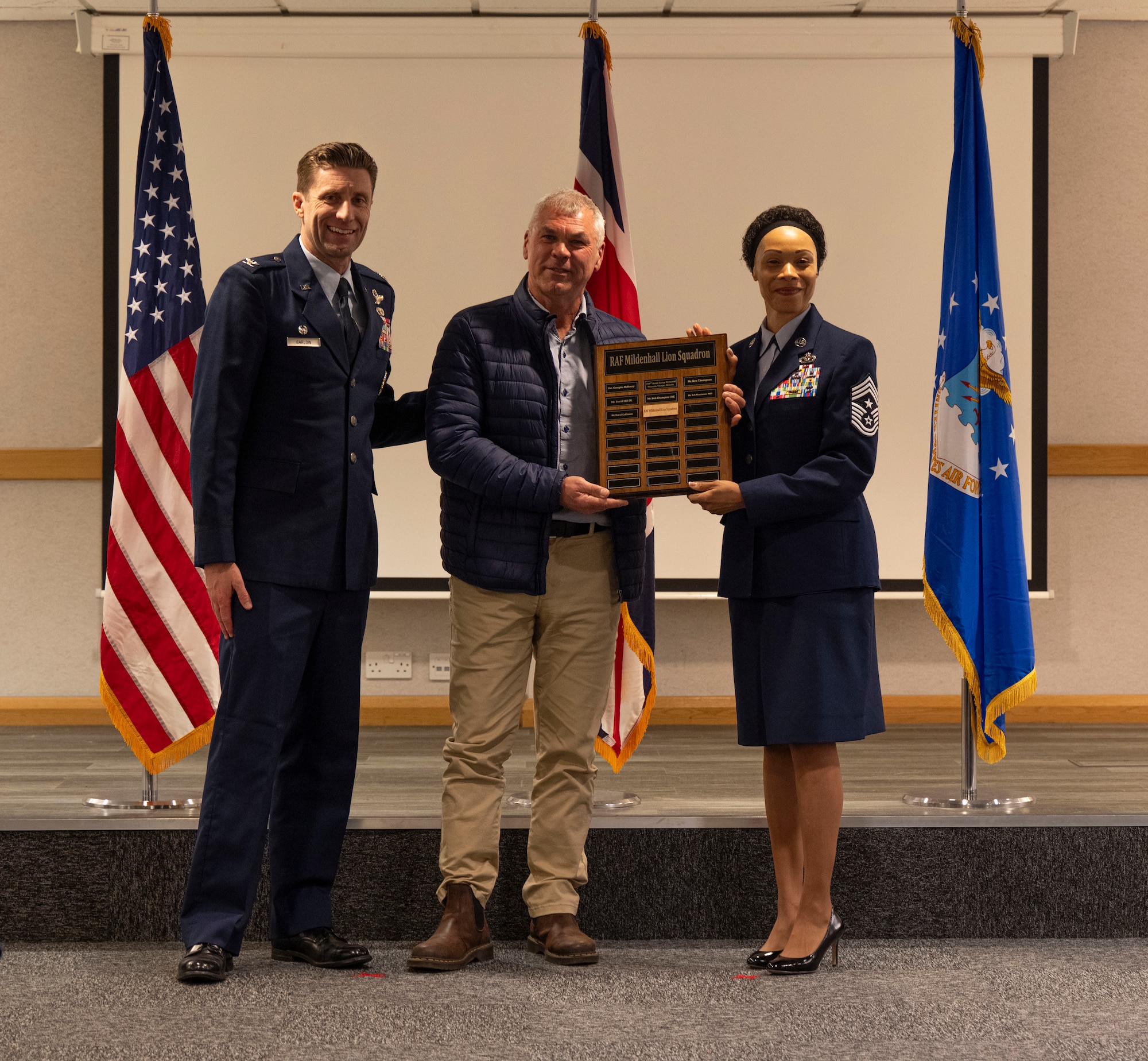 The 100th Air Refueling Wing command team presents a plaque to Andy King, center, Suffolk Lowland Search & Rescue chairman, after becoming a Lion Squadron member during the honorary commanders’ induction ceremony at RAF Mildenhall, England, March 21, 2025.