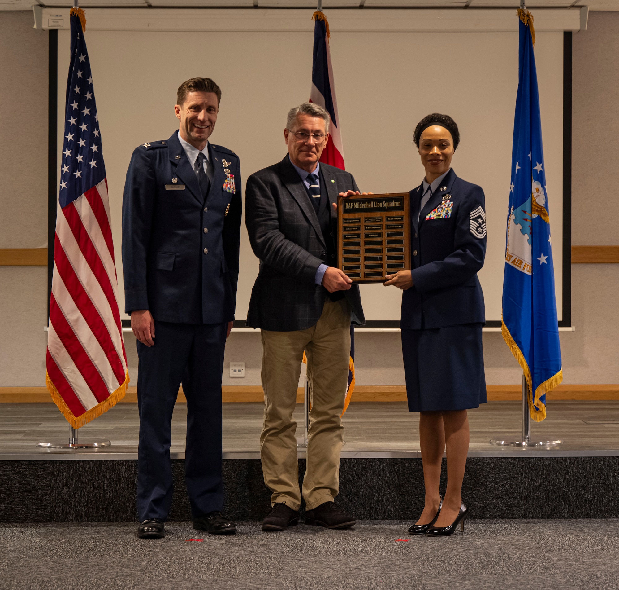 The 100th Air Refueling Wing command team presents a plaque to David Collinson, center, Retired Assistant Director for Planning and Regulatory Service, becoming a Lion Squadron member during the honorary commanders’ induction ceremony at RAF Mildenhall, England, March 21, 2025.
