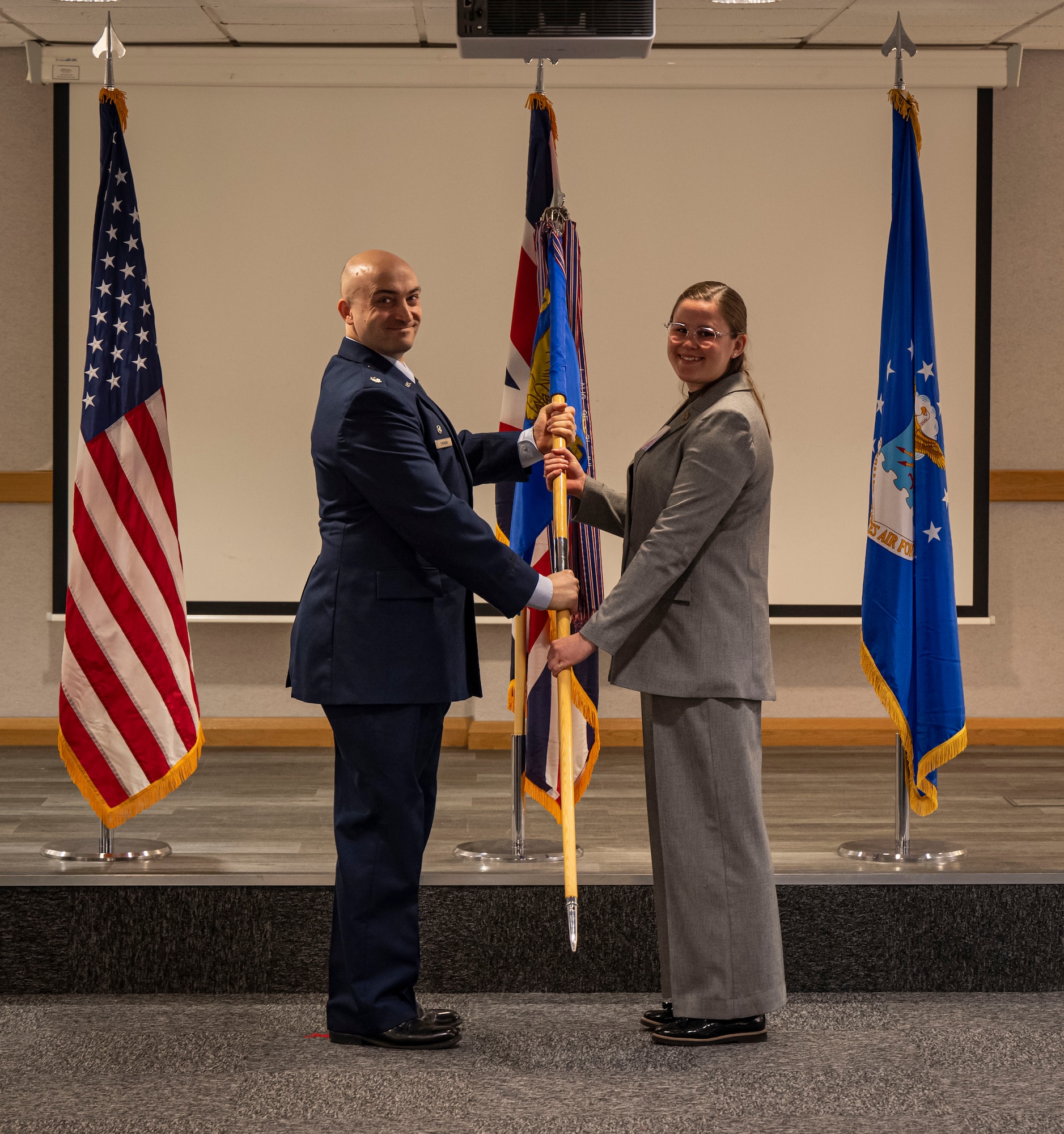 U.S. Air Force Lt. Col. Scott Engman, left, 100th Logistics Readiness Squadron commander, presents a guidon to Sophie Green, 95th Bomb Group Museum curator, during the honorary commanders’ induction ceremony at RAF Mildenhall, England, March 21, 2025.