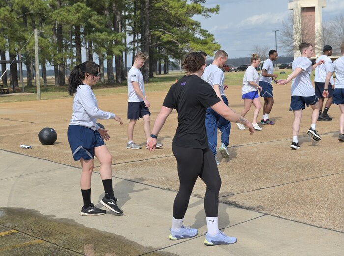 Lily Burns, Operational Support Team specialist helps Airmen execute proper stretches during a readiness exercise at Columbus Air Force Base, Mississippi, March. 13, 2025.