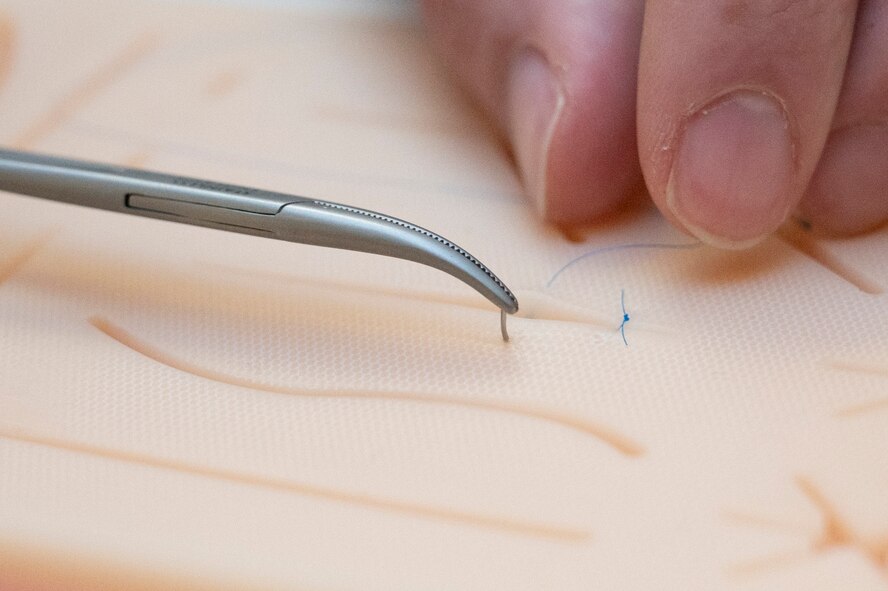 An Airman practices suturing on a training pad.