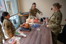 A 5th Medical Group Airman practices airway management procedures on a mannikin as other Airmen watch.