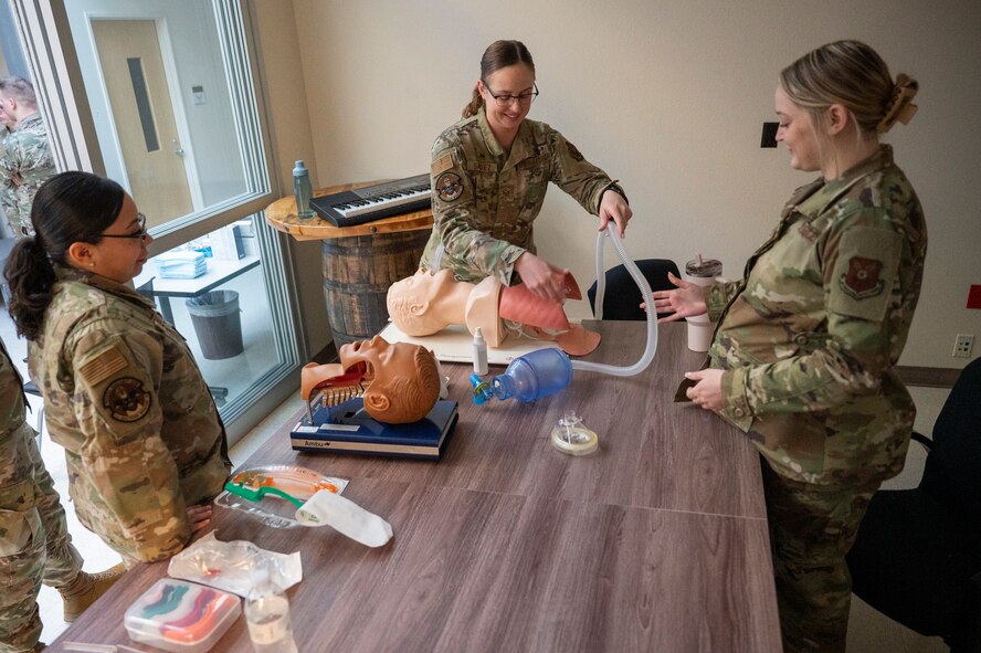 A 5th Medical Group Airman practices airway management procedures on a mannikin as other Airmen watch.