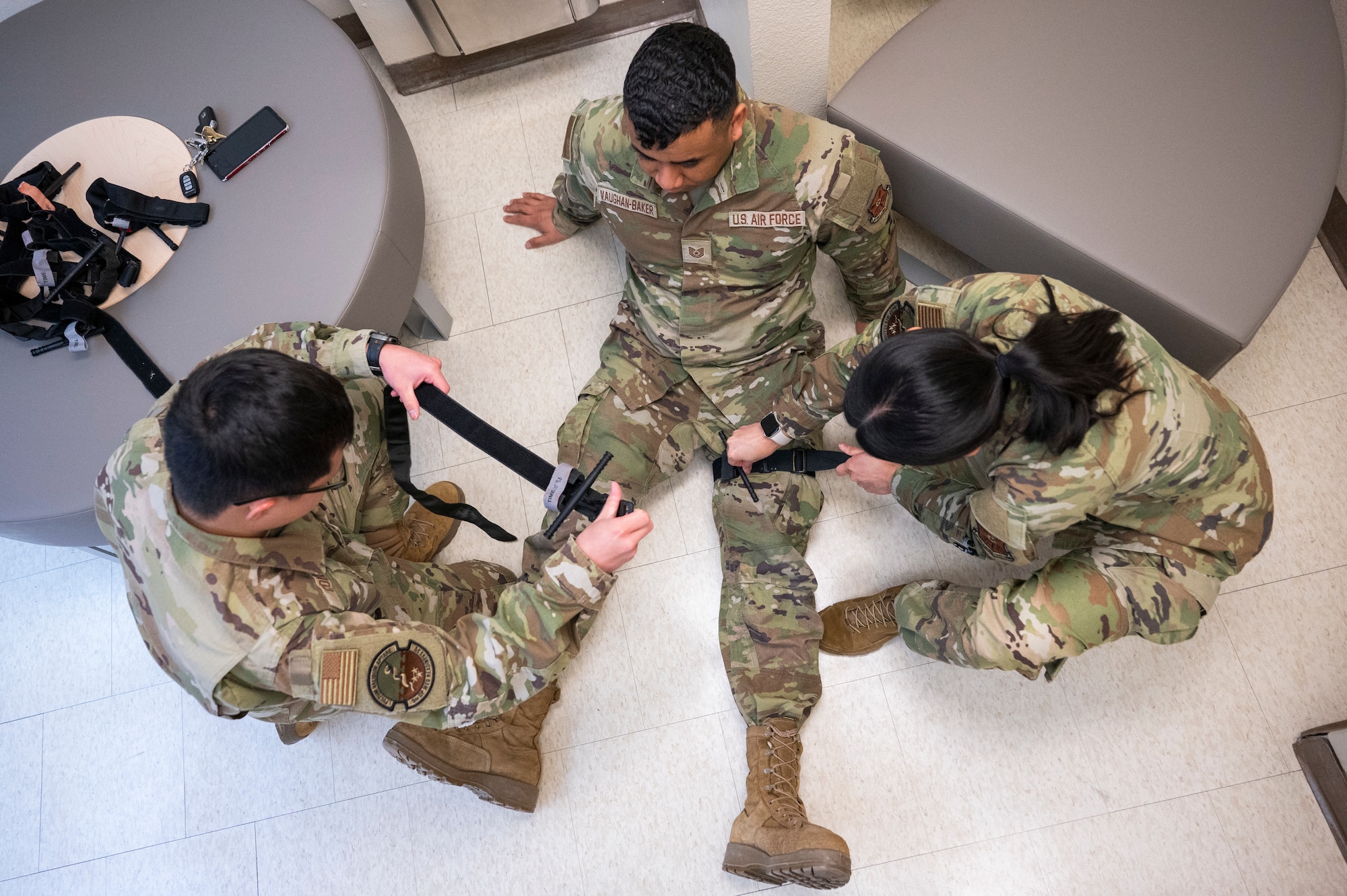 Two 5th Medical Group Airmen place a tourniquet on another Airman for training.