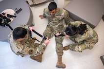 Two 5th Medical Group Airmen place a tourniquet on another Airman for training.
