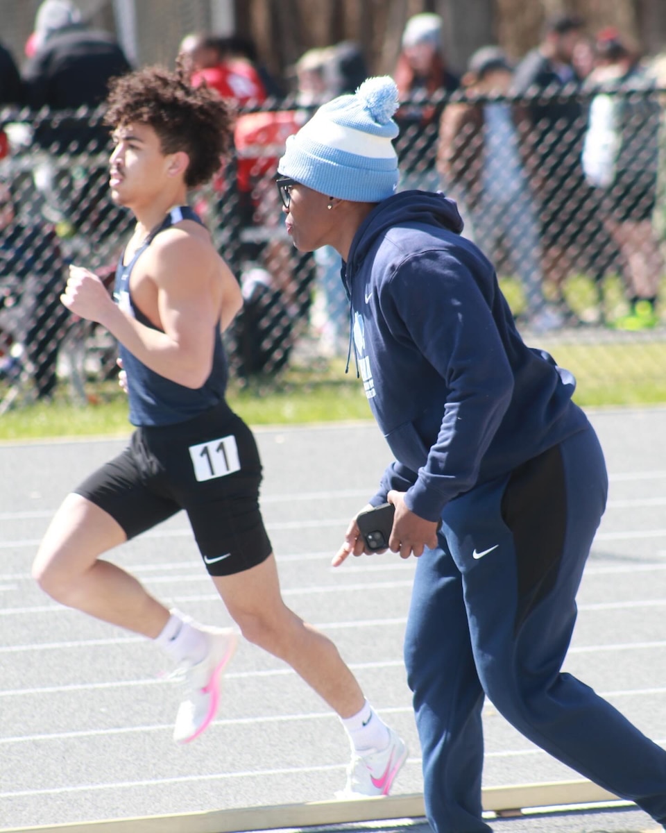 student runs at left while Todman, at right, motivates him during his run.