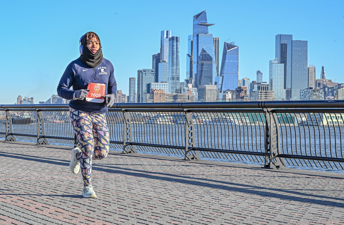 Todman running from left to right with railing and buildings behind her