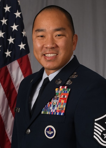 head and shoulders of Lin in service dress uniform in front of an American flag.