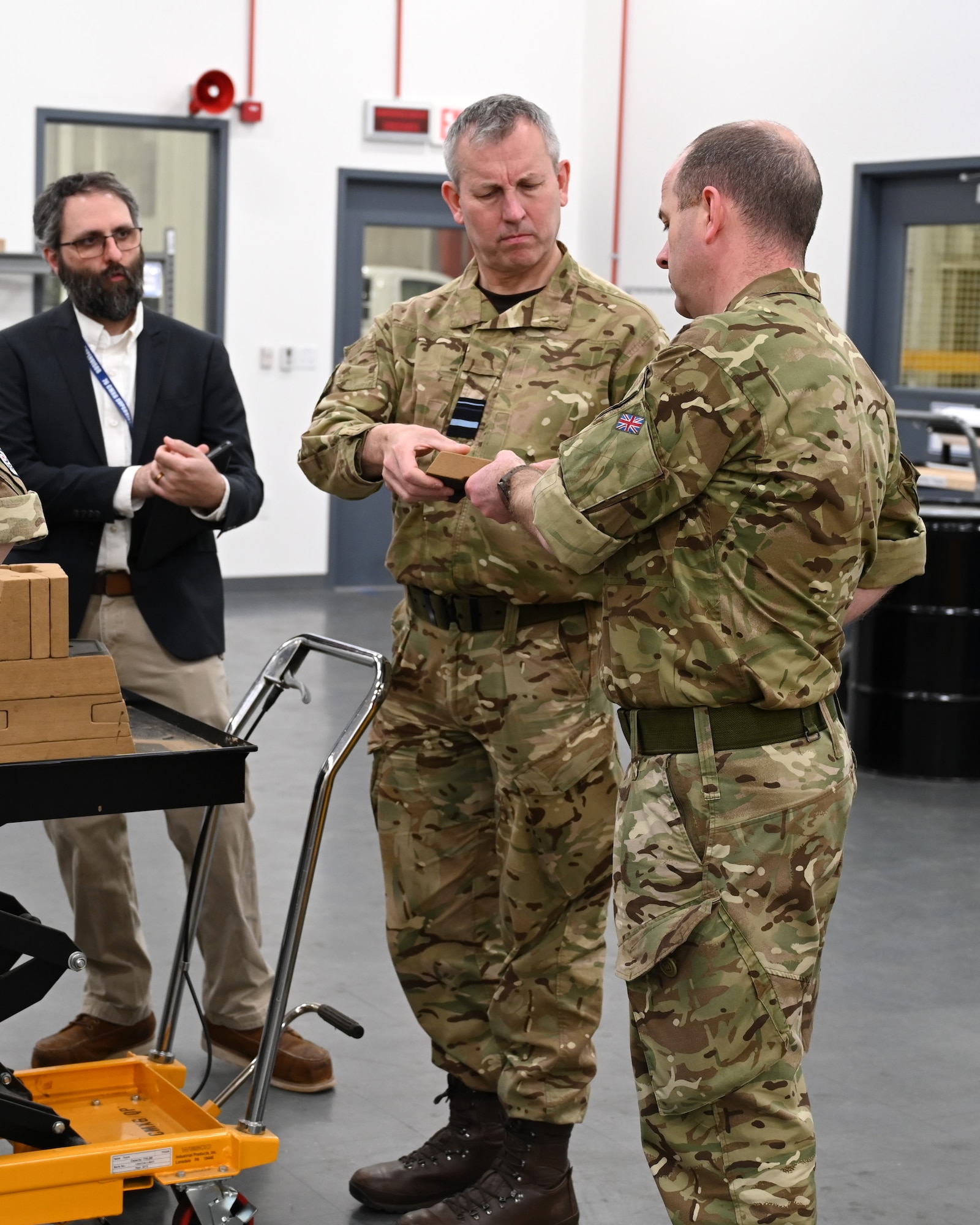 2 men in uniform holding a 3d part that looks like a tiny brick