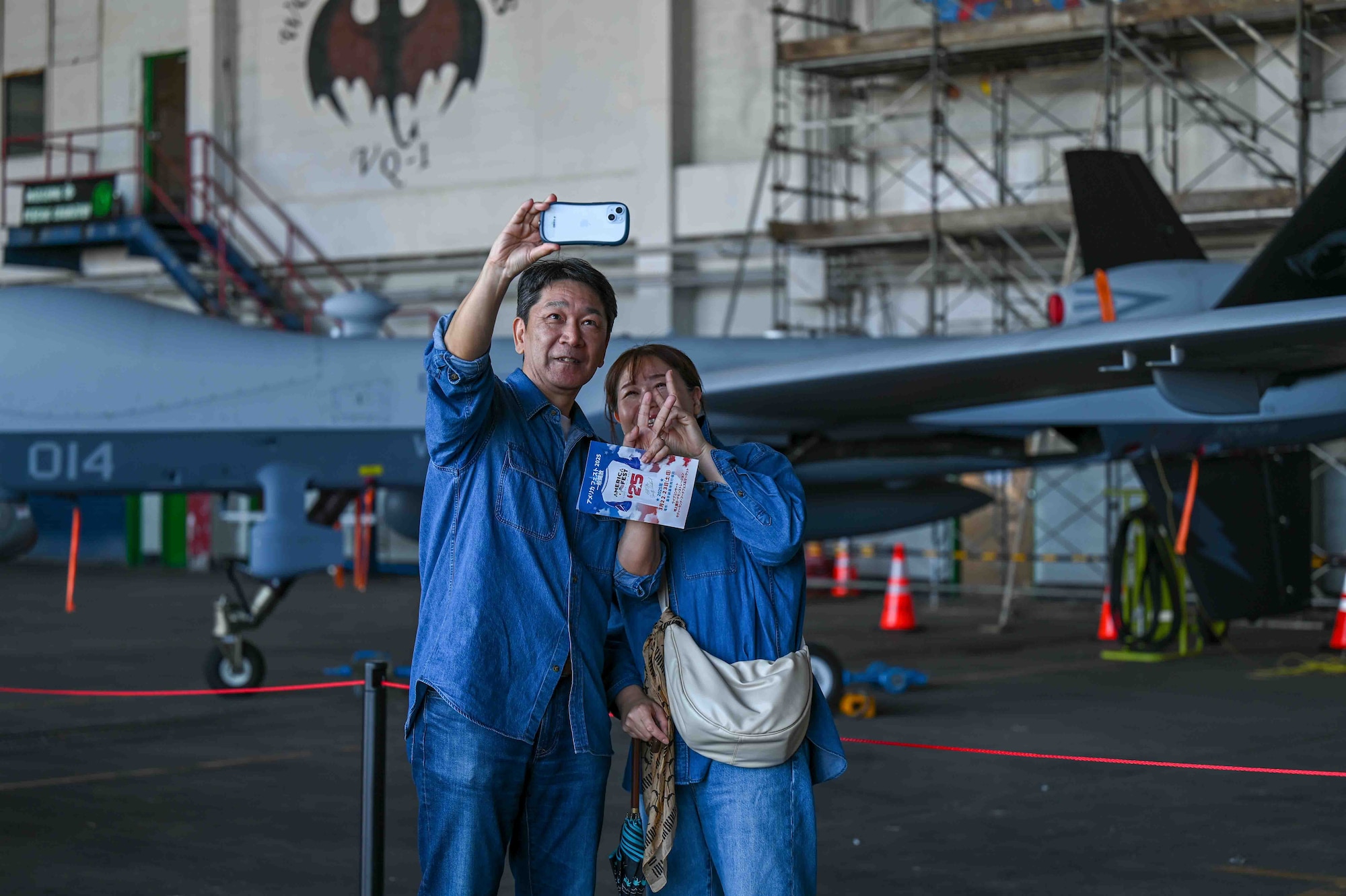 Two guests take a photo in front of an aircraft