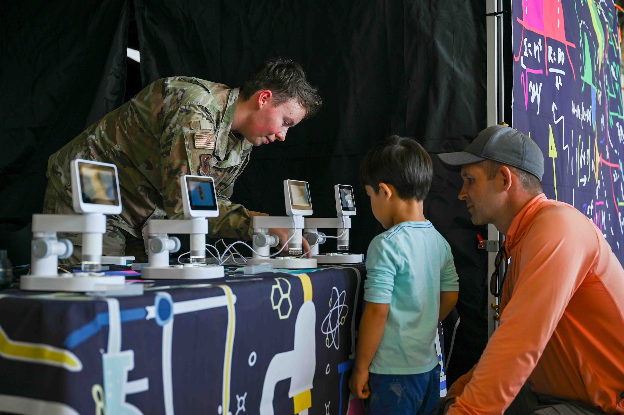A service member helps a child with the microscope