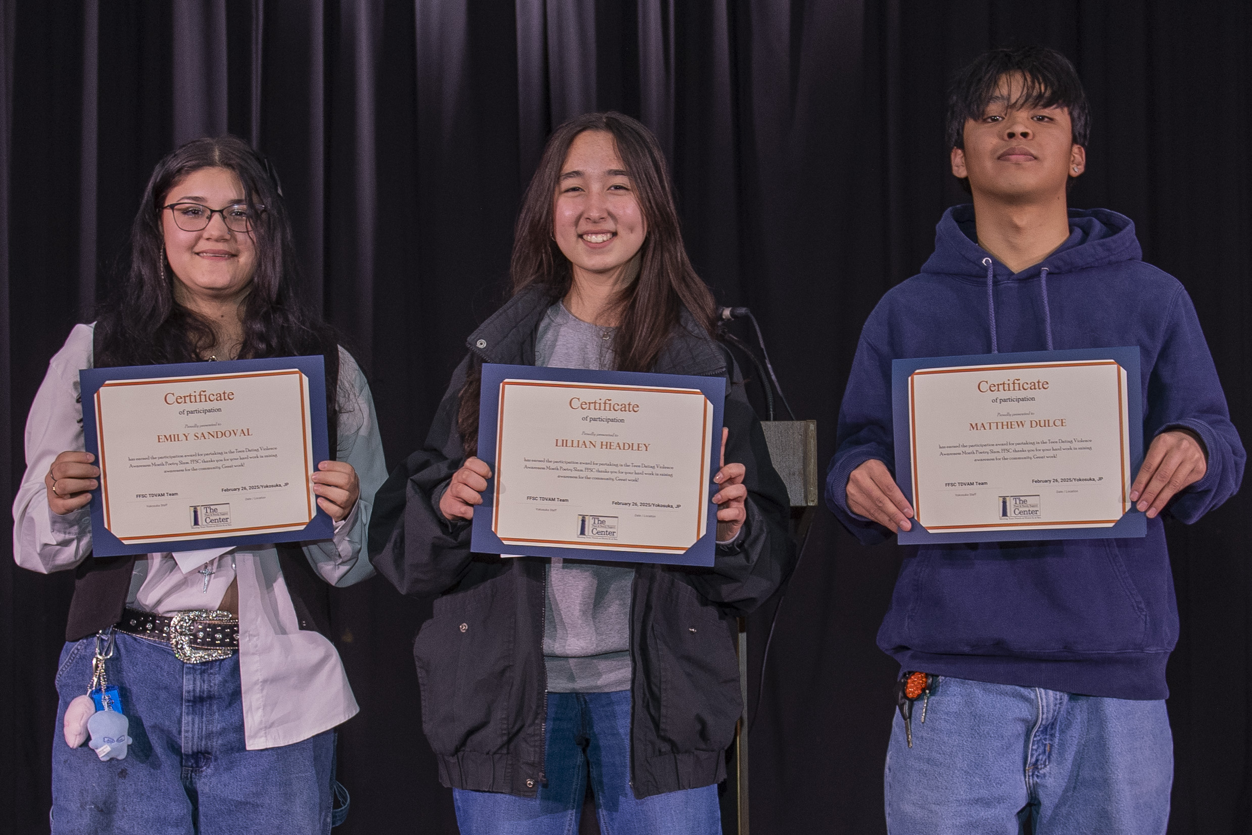 from left, Emily Sandoval, Lillian Headley and Matthew Dulce pose for a photo after participating in a poetry slam event hosted by Fleet and Family Support Center (FFSC) at Commander, Fleet Activities Yokosuka’s (CFAY) Nile C. Kinnick High School.