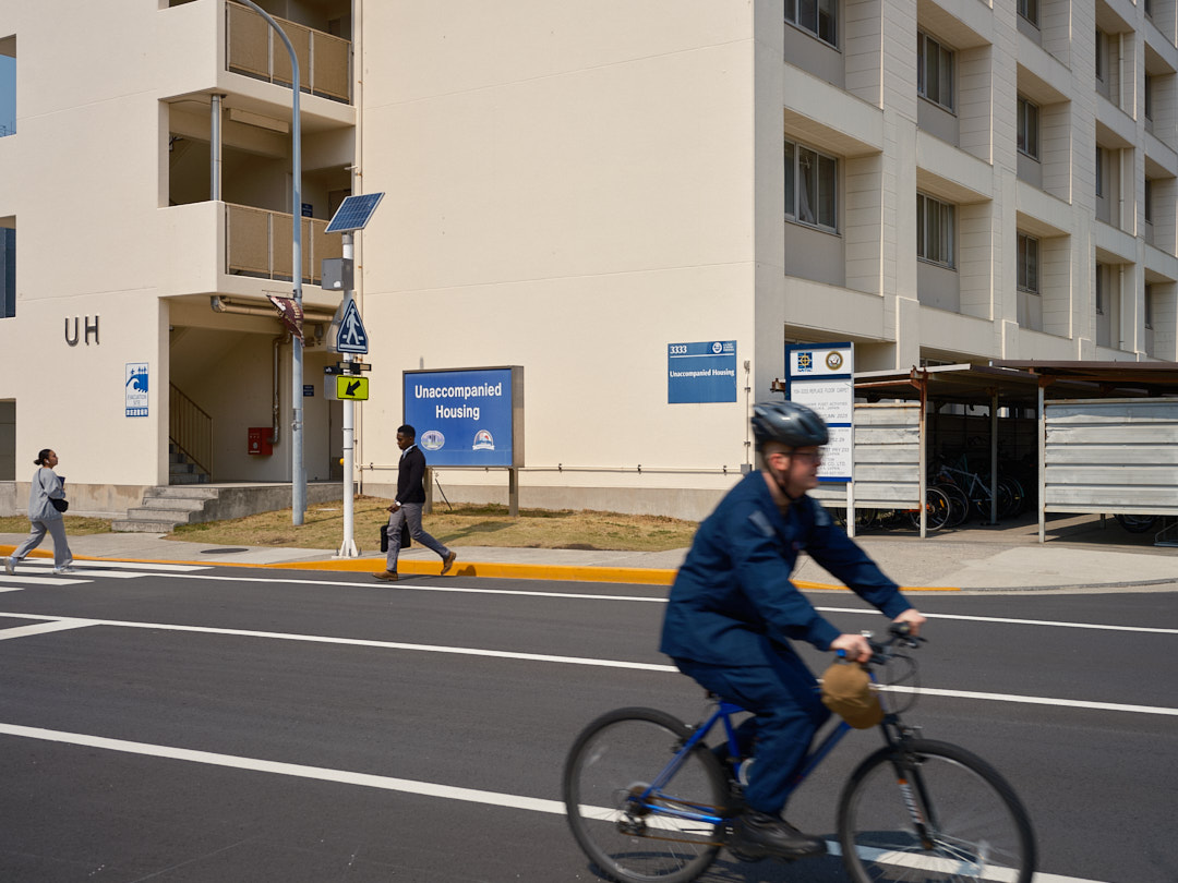 ailors and base community members transit outside Commander, Fleet Activities Yokosuka (CFAY) Unaccompanied Housing (UH) Building 3333 Tuesday, March 25, 2025.