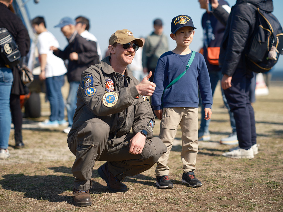 Lt. John Harnsberger, assigned to the Saberhawks of Helicopter Maritime Strike Squadron (HSM) 77, poses for a photo with a child at the 29th Annual Yokosuka Spring Festival throughout the installation Saturday, March 22, 2025.