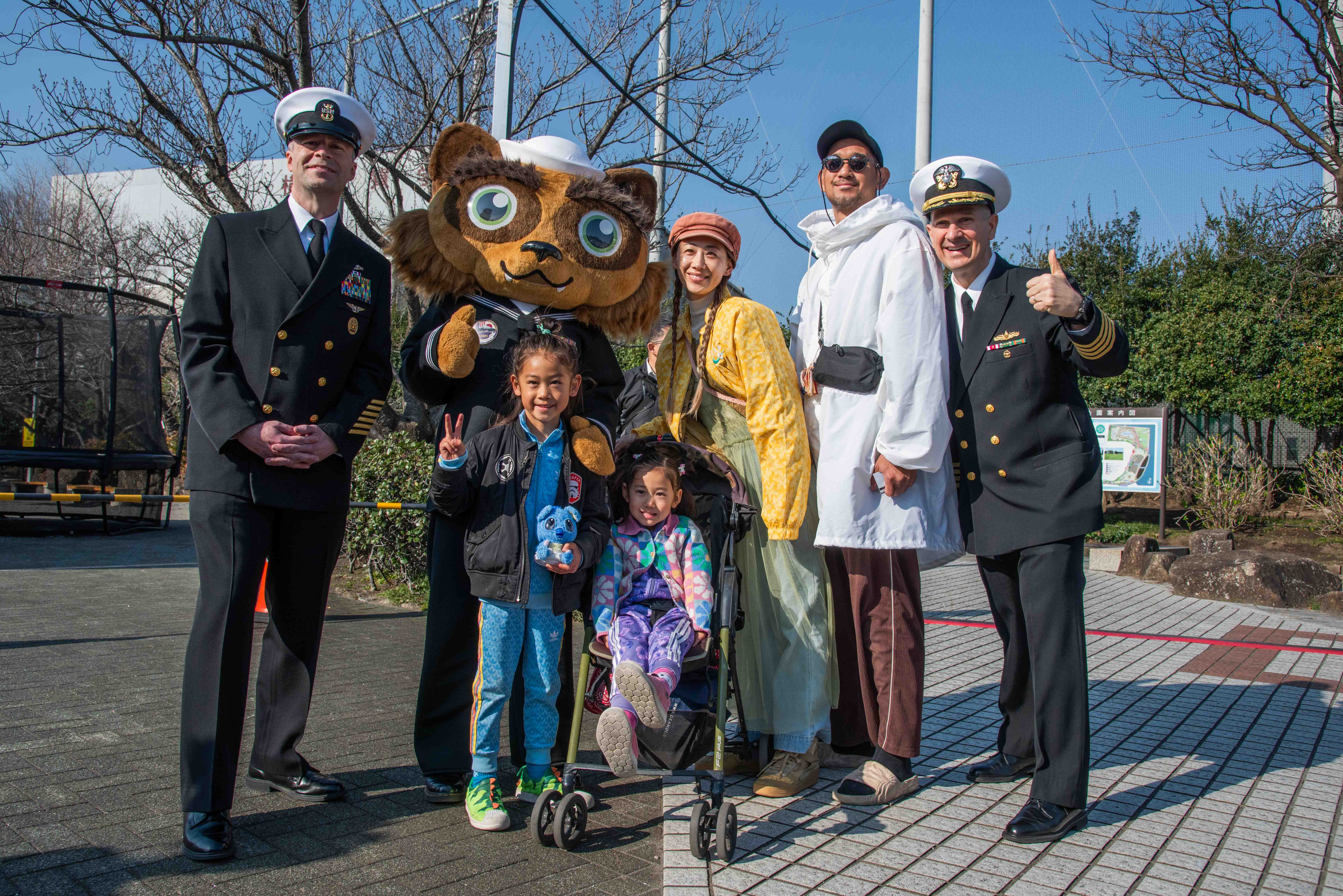 Command Master Chief Dennis Hunt, left, and Capt. Les Sobol, Commander, Fleet Activities Yokosuka (CFAY), right, pose for a photo with visitors of the 29th Yokosuka Spring Festival 2025.