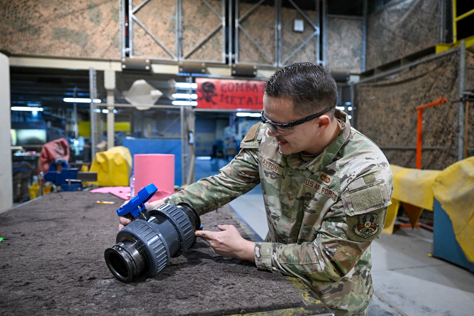 An Airman inspects a ball joint valve for pin holes.