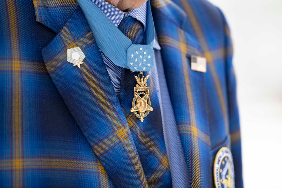 The suit and tie, adorned with the Medal of Honor and other pins, is shown in a close-up photo of a veteran's chest.